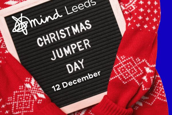 Christmas jumper with text board featuring Leeds Mind logo and text reading 'Christmas Jumper Day 12 December'